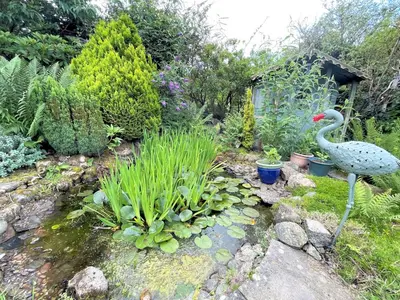 a garden with a statue of a swan in the grass at Traditional Scottish Cottage in Beautiful Location - Pass the Keys in Rockcliffe