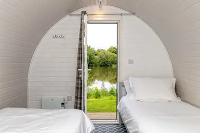 two beds in a room with an arched window at Broom Leisure Camping Pods in Annan