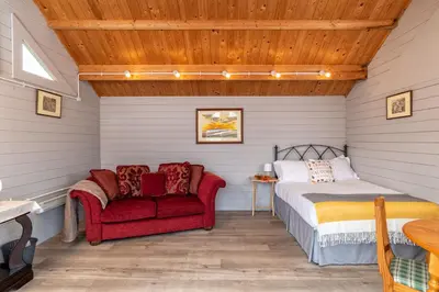 a bedroom with a bed and a red chair at Broom Leisure Camping Pods in Annan