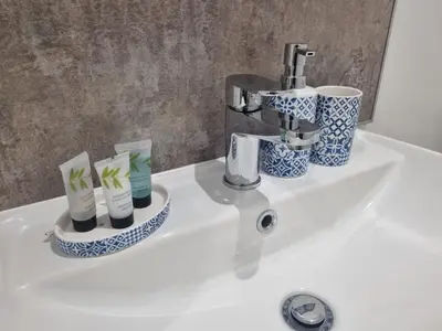 a bathroom sink with a faucet and cups on it at The Plough Inn in Carlisle
