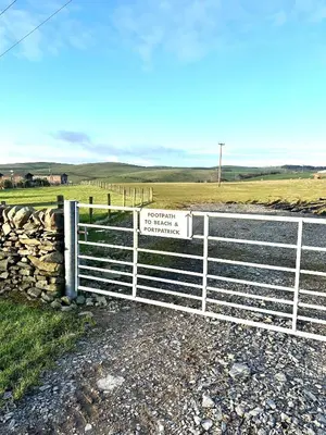 a fence with a sign on it next to a field at Lagavulin 3 in Portpatrick