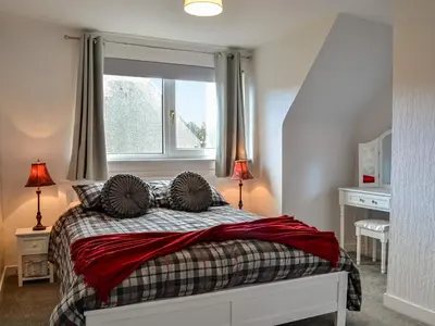 a bedroom with a bed with a window at Anchor Cottage in Portpatrick