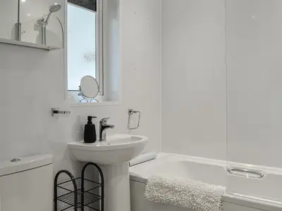 a white bathroom with a sink and a bath tub at Anchor Cottage in Portpatrick