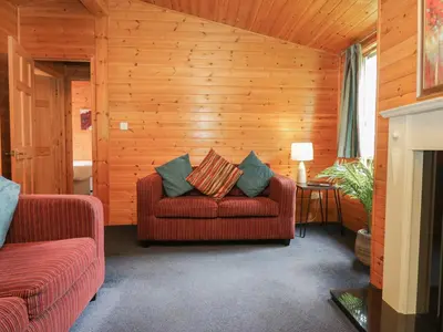 a living room with a red couch and wooden walls at Elm Lodge in Keswick