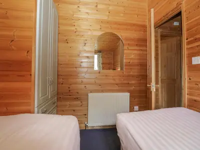 two beds in a room with wooden walls at Elm Lodge in Keswick