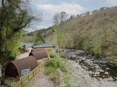 a river with two huts next to a river at Pod No 6 in Keswick