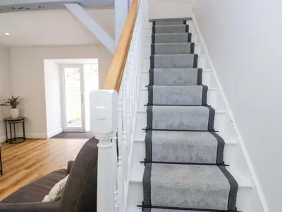 a winding staircase in a home with white walls and wood floors at Riverside Cottage No 4 in Keswick