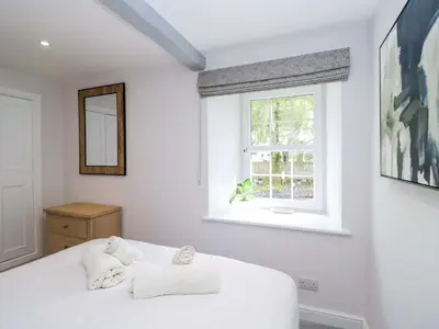 a white bedroom with a bed and a window at Riverside Cottage No 4 in Keswick