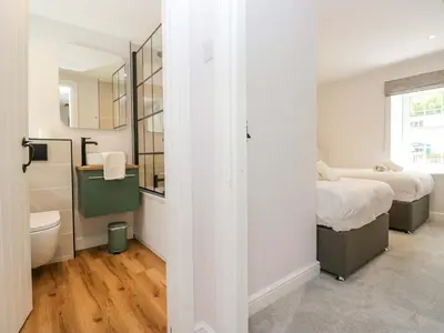 a bedroom with two beds and a bathroom with a mirror at Riverside Cottage No 4 in Keswick