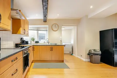 a kitchen with wooden cabinets and a black refrigerator at Hummingbird House in Cockermouth
