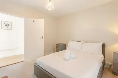 a bedroom with a large bed with white sheets at Hummingbird House in Cockermouth