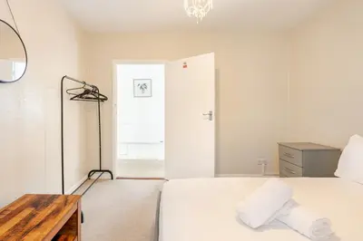 a white bedroom with a bed and a mirror at Hummingbird House in Cockermouth