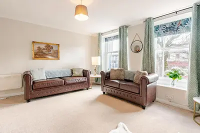 a living room with two leather couches and a window at Hummingbird House in Cockermouth