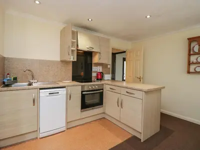 a kitchen with white appliances and wooden cabinets at Beech Timber Lodge in Keswick