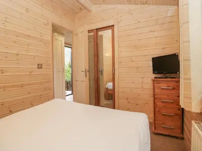 a bedroom with a bed and a flat screen tv at Canadian Cabin No 39 in Keswick