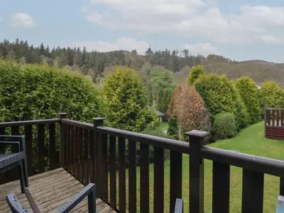 a wooden deck with a view of a garden at Canadian Cabin No 39 in Keswick