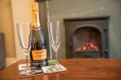 a bottle of wine and two champagne glasses on a table at 25 Church Street in Keswick