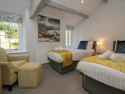 a hotel room with two beds and a chair at Greta House in Keswick