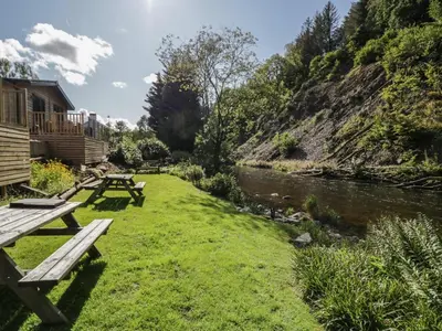 a picnic table in the grass next to a river at Briery House in Keswick