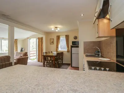 a kitchen and living room with a table and chairs at Chestnut Timber Lodge in Keswick