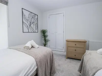 a white bedroom with two beds and a dresser at Riverside Cottage No 3 in Keswick