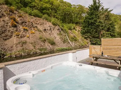 a jacuzzi tub with a bench next to a hill at Riverside Cottage No 3 in Keswick