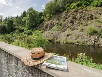 a straw hat and a magazine sitting on a bridge at Riverside Cottage No 3 in Keswick