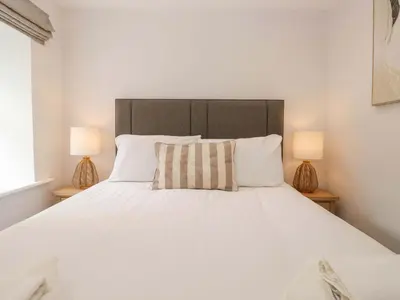 a bedroom with a large white bed with two lamps at Riverside Cottage No 5 in Keswick