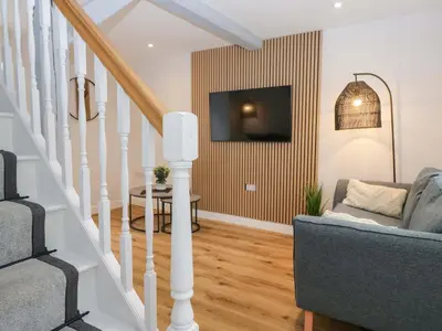 a living room with a couch and a tv on a wall at Riverside Cottage No 5 in Keswick