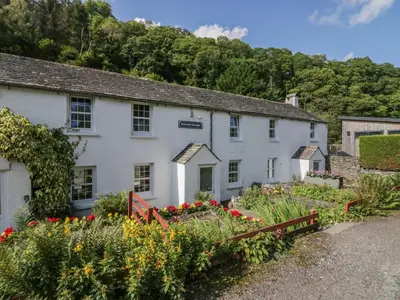 a white house with flowers in front of it at Riverside Cottage No 5 in Keswick