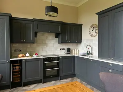 a kitchen with gray cabinets and a clock on the wall at Geltsdale Wing, Wetheral 1st floor apartment with countryside views, close to pub & restaurant in Wetheral