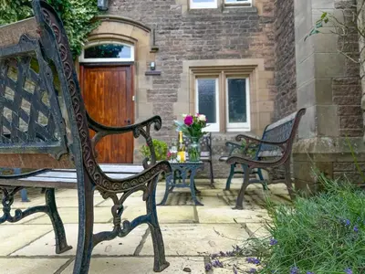 two benches sitting on a patio with a table with flowers at Geltsdale Wing, Wetheral 1st floor apartment with countryside views, close to pub & restaurant in Wetheral