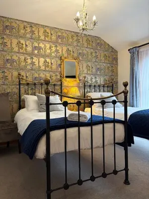 a bedroom with a bed and a wall with wallpaper at Elm Tree Lodge in Keswick