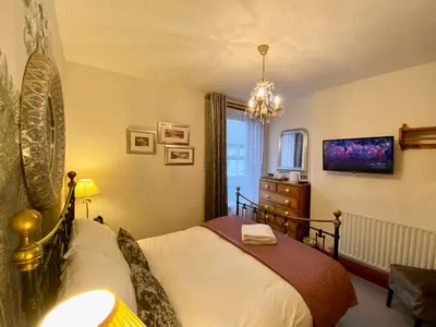 a bedroom with a bed and a chandelier at Elm Tree Lodge in Keswick