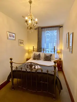 a bedroom with a bed with a chandelier and a window at Elm Tree Lodge in Keswick