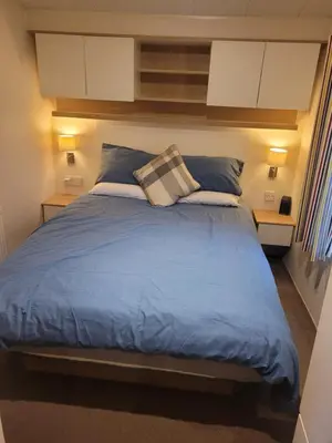a bedroom with a large bed with blue sheets and pillows at Arual Caravan Manor House Park. Allonby, Cumbria in Maryport