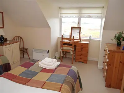 a bedroom with a bed and a dresser and a mirror at Airie Farmhouse in Castle Douglas