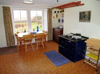 a kitchen and dining room with a table and a table and chairs at Airie Farmhouse in Castle Douglas