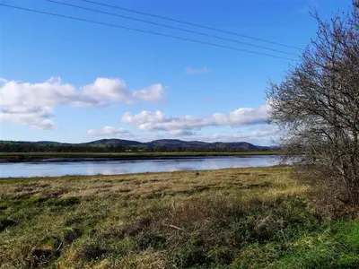 a view of a river with mountains in the background at Branta Cottage in Dumfries