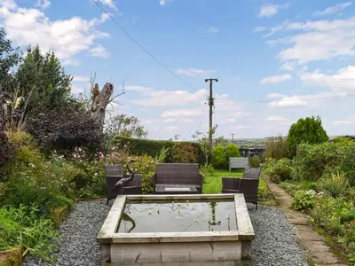 a garden with three chairs and a pond in a yard at Swinside Cottage in Ennerdale Bridge