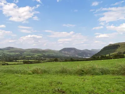 a field of green grass with mountains in the background at Swinside Cottage in Ennerdale Bridge