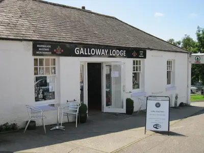 a building with a table and chairs in front of it at Laghead Cottage in Gatehouse of Fleet