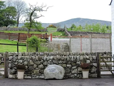 a stone wall with a bench next to a fence at Criffel Glen in Dumfries
