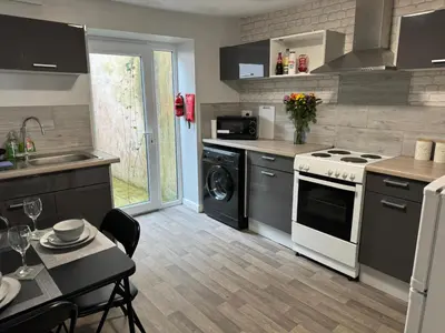 a kitchen with a white stove top oven next to a table at Scotch Terrace - 3 Bedrooms - Sleeps 6 in Whitehaven