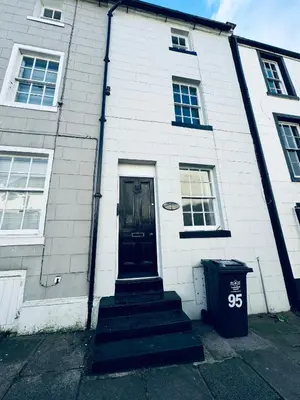 a white building with a black door and a trash can at Scotch Terrace - 3 Bedrooms - Sleeps 6 in Whitehaven