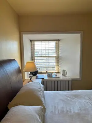a bedroom with a bed and a window and a lamp at Moresby Hall Country House Hotel in Whitehaven