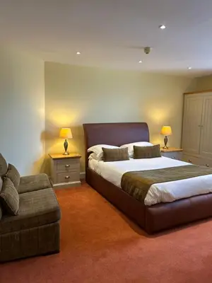 a bedroom with a large bed and a couch at Moresby Hall Country House Hotel in Whitehaven