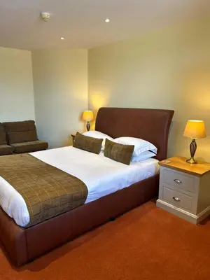 a bedroom with a large bed and a couch at Moresby Hall Country House Hotel in Whitehaven