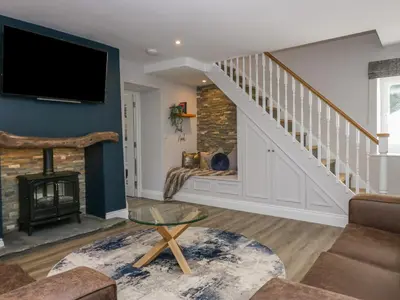 a living room with a staircase and a fireplace at Garden Cottage No 1 in Keswick