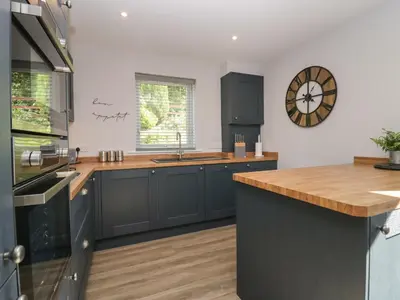 a kitchen with blue cabinets and a clock on the wall at Garden Cottage No 1 in Keswick